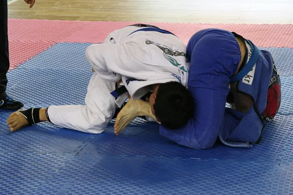 Chave de braço numa competição de jiu-jitsu de quimono.